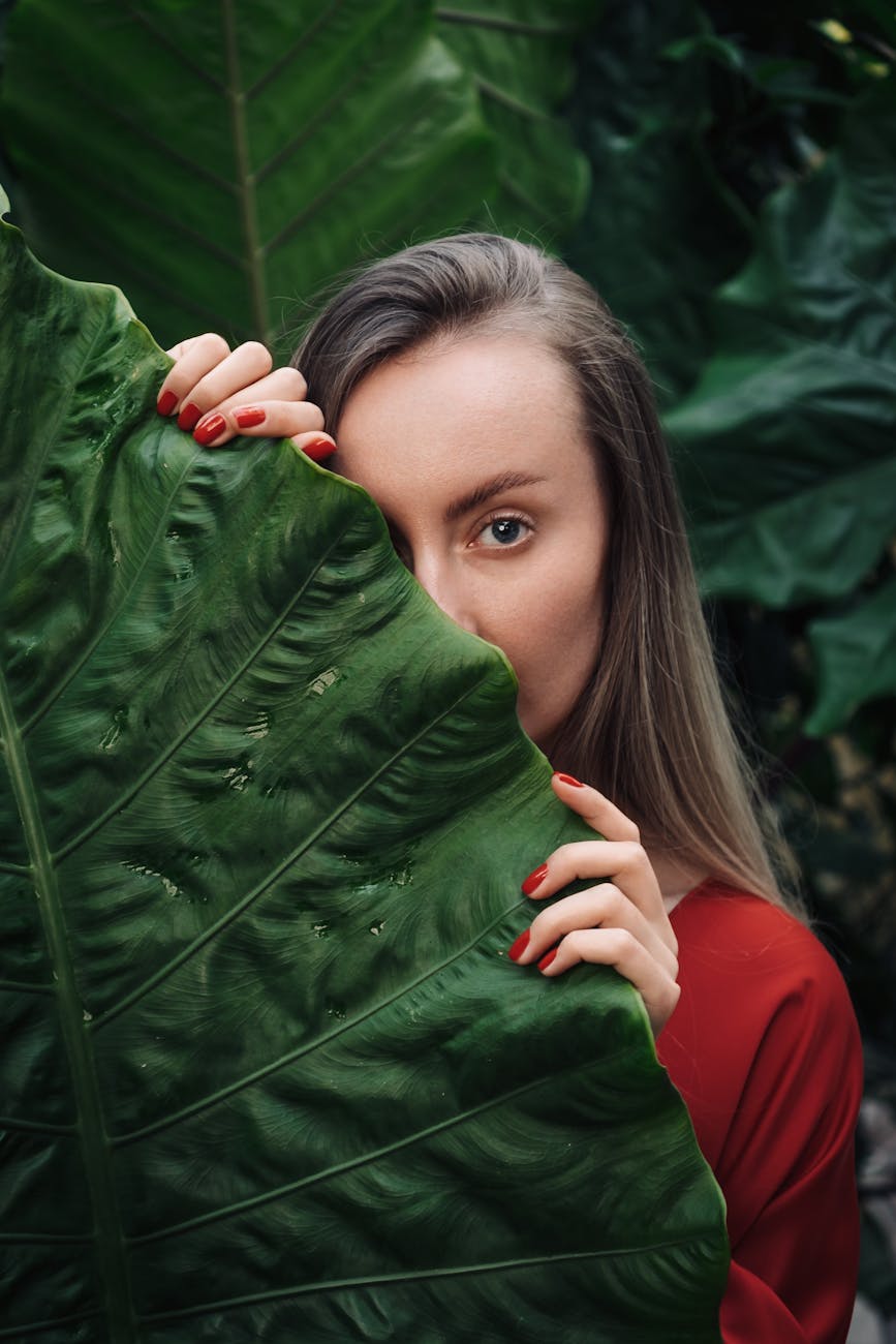woman in red long sleeve shirt holding green leaf